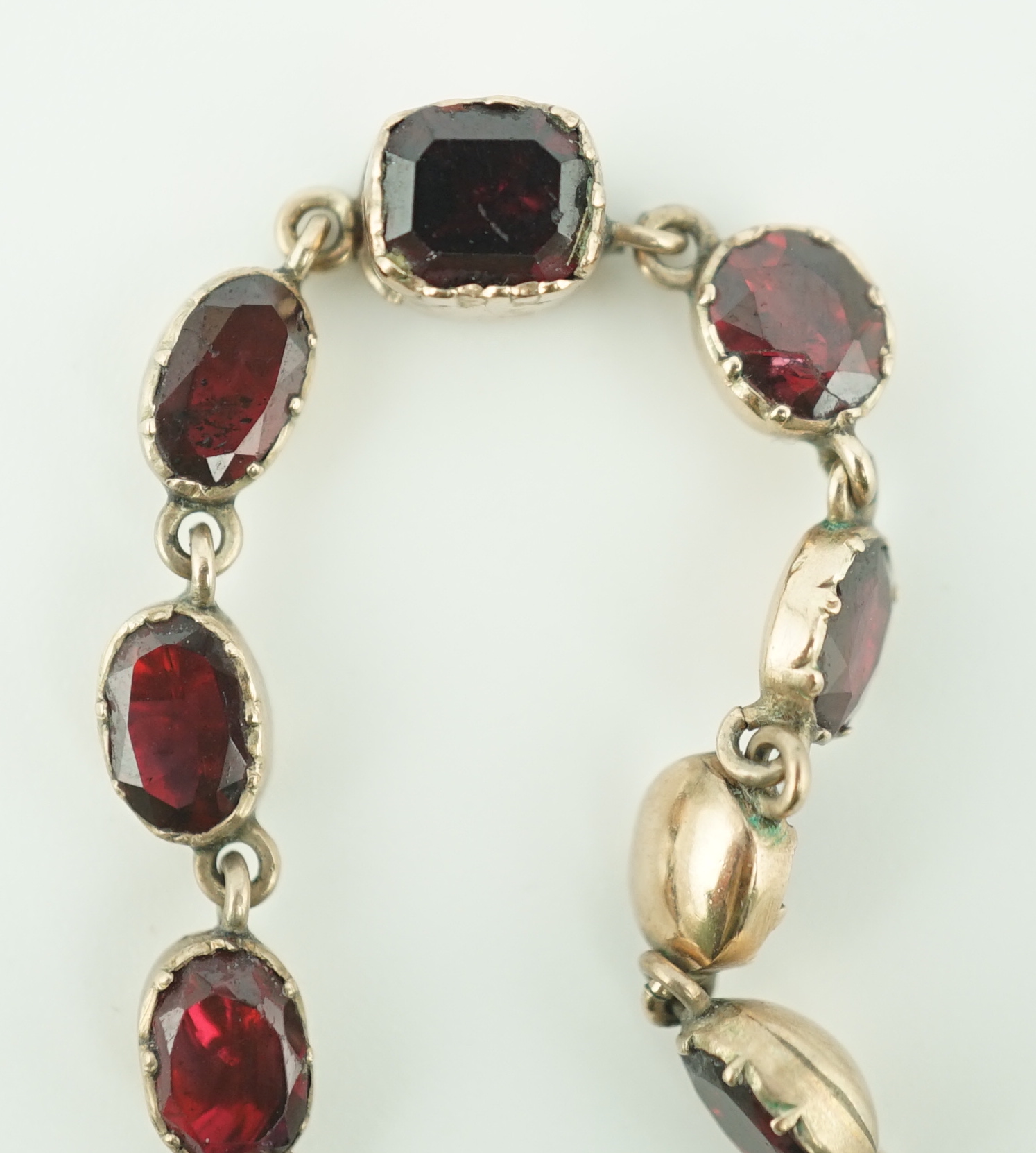 An early 19th century gold, and thirty five graduated foil backed garnet set necklace, with later garnet and seed pearl set drop